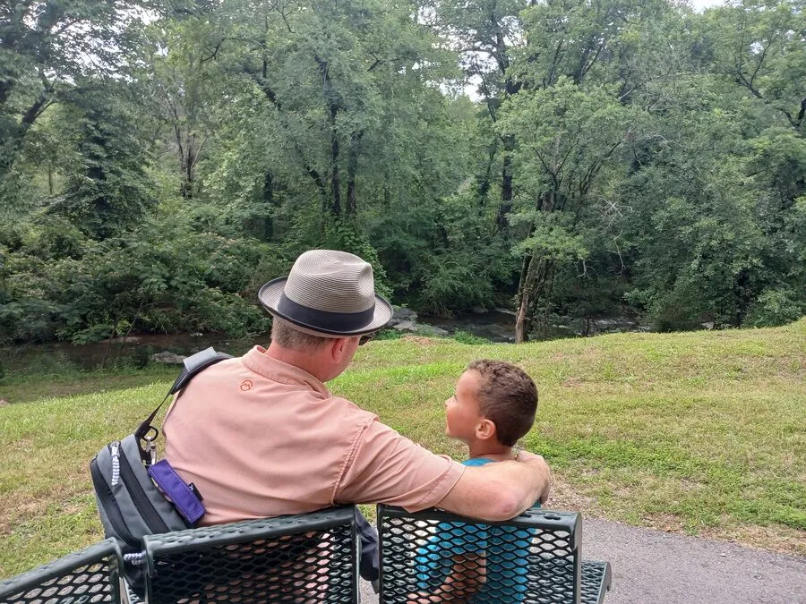 Jared and Levi sitting on a bench above a creek, mid-conversation