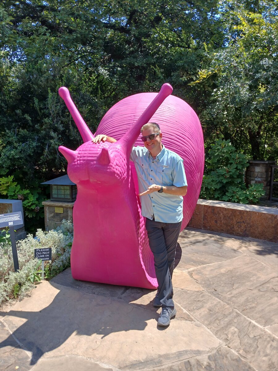 Jared posing proudly next to a giant pink snail sculpture